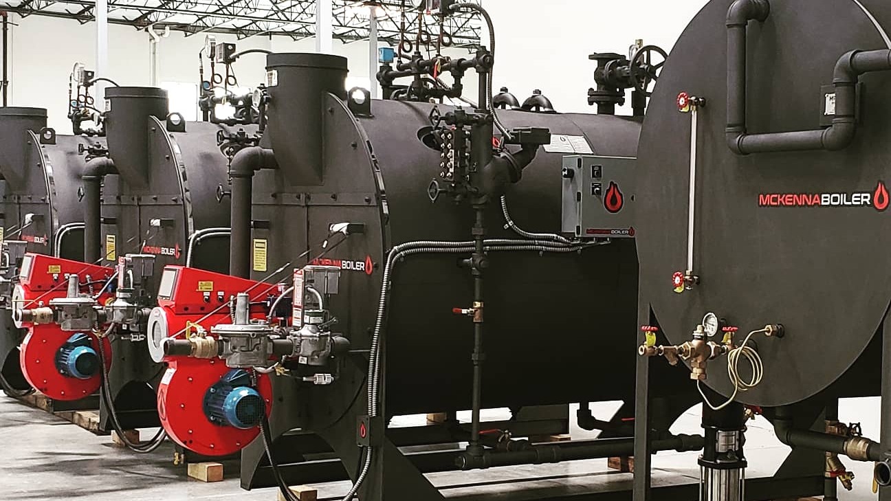 McKenna firetube boilers with red burners lined up in the shop